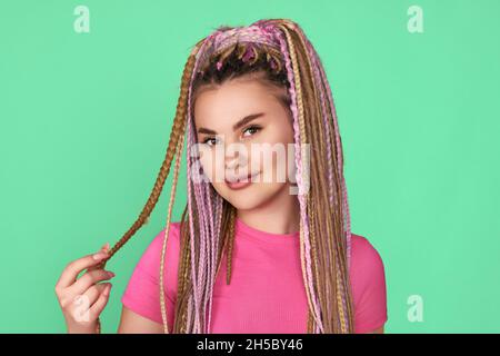 Frau mit Dreadlocks lächelt auf grünem Hintergrund Stockfoto