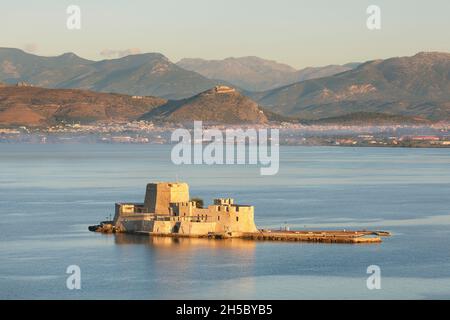 Die Festung von Bourtzi in der Bucht vor der Stadt Nafplio mit der antiken Stätte Argos in der Ferne auf dem Peloponnes von Griechenland Stockfoto