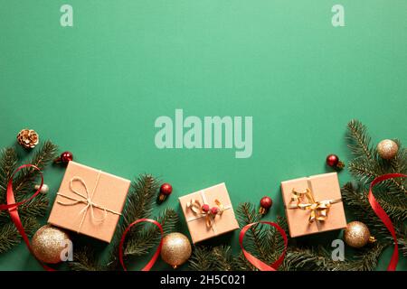 weihnachts-Geschenkboxen mit weihnachts-Accessoires auf grünem Hintergrund. Vorbereitung auf die Feiertage. Draufsicht mit Kopierbereich. Stockfoto