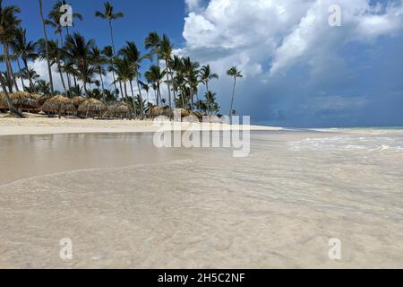 Paradiesischer tropischer Strand und Ozean, Blick auf weißen Sand, Kokospalmen über Sonnenschirmen und Liegestühlen. Badeort, Urlaub auf malerischer Insel Stockfoto