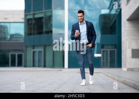 Selbstbewusster arabischer Kerl Programmierer mit Rucksack zu Fuß durch die Straße Stockfoto