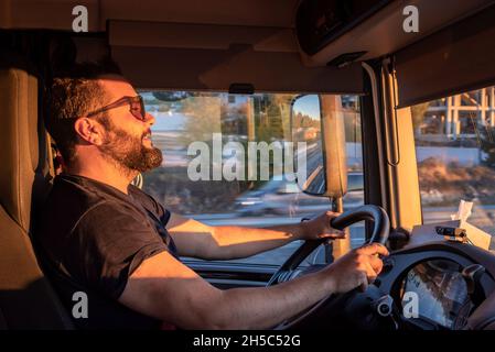 Schwerer Lkw-Fahrer glücklich, in der Lage sein, einen LKW zu fahren, und macht die Geste der OK, mit dem Daumen nach oben. Stockfoto