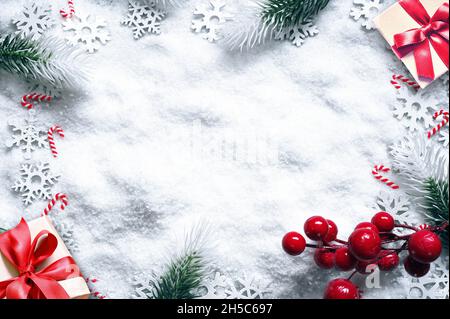 Tannenzweige mit weihnachtlichen Dekorationen auf weißem, schneebedecktem Hintergrund. Urlaubskonzept. Stockfoto