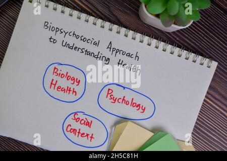 Biopsychosozialer Ansatz zum Verständnis der Gesundheitsmethode Schreiben Sie auf ein Buch isoliert auf Holztisch. Stockfoto