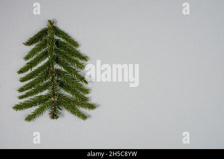 Stilisierter Weihnachtsbaum aus Tannenzweigen auf grauem Hintergrund. Stockfoto