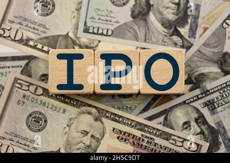 ipo (Initial Public Offering) Thema. Holzwürfel mit dem Akronym ipo, auf dem Hintergrund von Dollarscheinen. ipo Geschäftskonzept Stockfoto