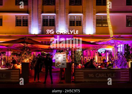 Miami Beach, USA - 20. Januar 2021: Art-Deco-Viertel in der Nacht mit neonrosa Lichtzeichen des Restaurants Carlyle in South Beach, Florida OCE Stockfoto