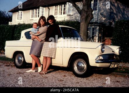 Zwei junge Frauen posieren mit einem cremefarbenen Ford Anglia im September 1965 Foto von Tony Henshaw Archive Stockfoto