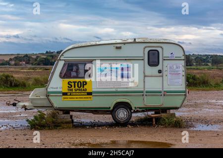 Oldtimer-Wohnwagen auf brancaster Beach-Parkplatz für den Parkplatzwächter als Büro verwendet, Coronavirus-Warnung, stoppen die Ausbreitung von covid, Nachrichten. Stockfoto