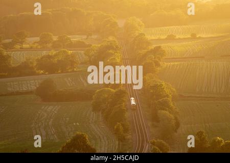 Zug durch englische Landschaft, Surrey, Abendlicht, hoher Aussichtspunkt, North Downs Line. Sonnenlicht, das auf Schienen scheint Stockfoto