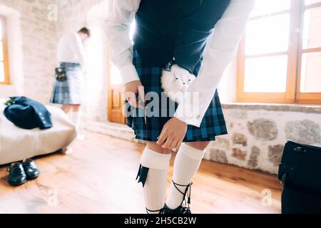 Ein Mann in schottischer Nationaltracht bereitet sich auf eine Hochzeitszeremonie in einem Hotelzimmer vor Stockfoto