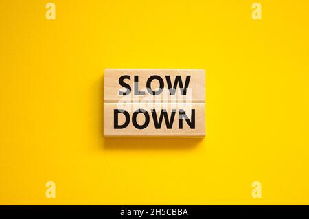 Zeit zum Verlangsamen des Symbols. Konzeptwörter verlangsamen sich auf Holzblöcken auf einem schönen gelben Hintergrund. Business und Slow-Down-Konzept. Speicherplatz kopieren. Stockfoto