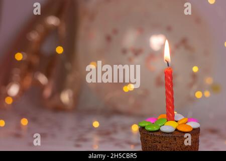 Geburtstagsfeier mit Cupcakes auf brennender Kerze. Mit Ballons und Lichtern auf Bokeh Hintergrund Stockfoto