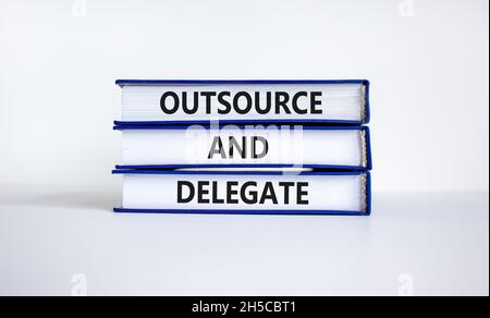 Outsourcing und Delegiertensymbol. Konzeptwörter „outsourcen und delegieren“ in Büchern. Schöner weißer Hintergrund. Business-, Outsourcing- und Delegiertenkonzept, Stockfoto