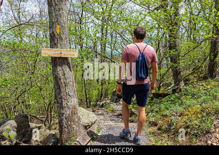 Ein junger Mann mit Kordelzug Tasche Rucksack zu Fuß auf Wintergreen Skigebiet Dorf Stadt Natur Highlands Freizeit Wanderweg im Wald von Virginia Stockfoto