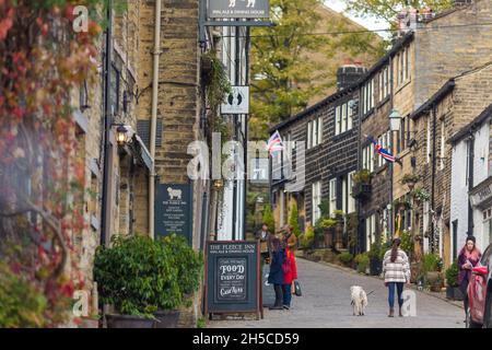 Haworth ist ein Touristenziel, das für seine Verbindung mit den Schwestern von Brontë und das erhaltene Erbe Keighley und Worth Valley Railway bekannt ist. Das Dorf liegt in den Pennine Hills von West Yorkshire in Großbritannien und ist bekannt für seine steile Kopfsteinpflasterstraße. Stockfoto