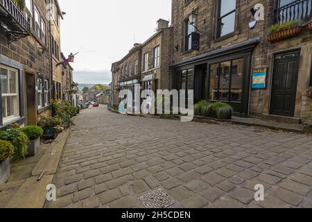 Haworth ist ein Touristenziel, das für seine Verbindung mit den Schwestern von Brontë und das erhaltene Erbe Keighley und Worth Valley Railway bekannt ist. Das Dorf liegt in den Pennine Hills von West Yorkshire in Großbritannien und ist bekannt für seine steile Kopfsteinpflasterstraße. Stockfoto