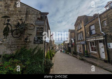 Haworth ist ein Touristenziel, das für seine Verbindung mit den Schwestern von Brontë und das erhaltene Erbe Keighley und Worth Valley Railway bekannt ist. Das Dorf liegt in den Pennine Hills von West Yorkshire in Großbritannien und ist bekannt für seine steile Kopfsteinpflasterstraße. Stockfoto