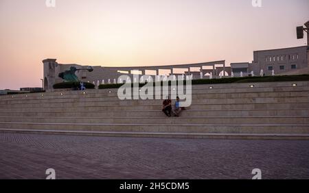 Das Amphitheater im Katara Cultural Village, Doha , Katar Panoramablick bei Sonnenuntergang mit Force of Nature 2 Statue und Menschen sitzen und gehen Stockfoto