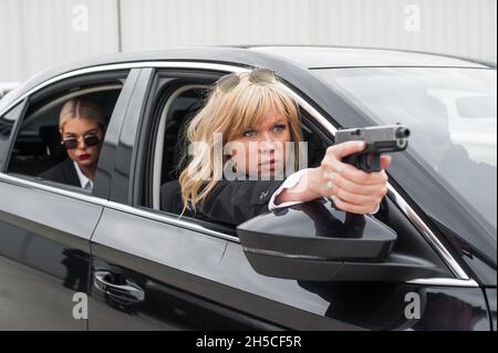 Professionelle bewaffnete Team von weiblichen und männlichen Bodyguards schießen und schützen eine VIP-Prominenten Person in der Auto-Limousine. Bodyguard und VIP Person Security Pro Stockfoto