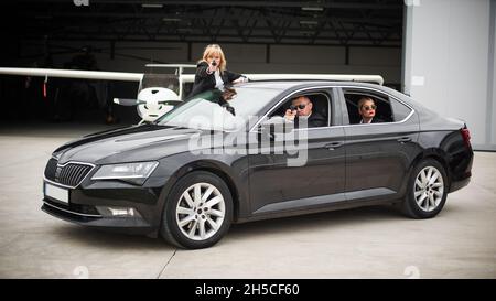 Professionelle bewaffnete Team von weiblichen und männlichen Bodyguards schießen und schützen eine VIP-Prominenten Person in der Auto-Limousine. Bodyguard und VIP Person Security Pro Stockfoto