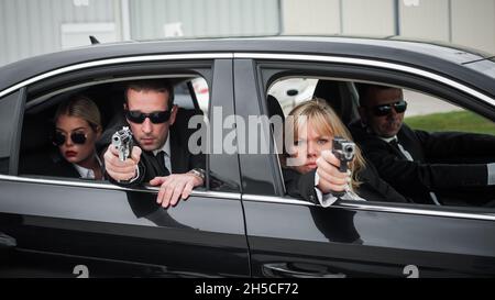 Professionelle bewaffnete Team von weiblichen und männlichen Bodyguards schießen und schützen eine VIP-Prominenten Person in der Auto-Limousine. Bodyguard und VIP Person Security Pro Stockfoto