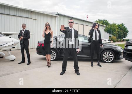 Ein professionelles Team von weiblichen und männlichen Leibwächtern schützt die berühmte prominente Person der Öffentlichkeit. Schließen Sie den Sicherheitsschutz. Polizeiagent in Zivil-Schwarz Stockfoto