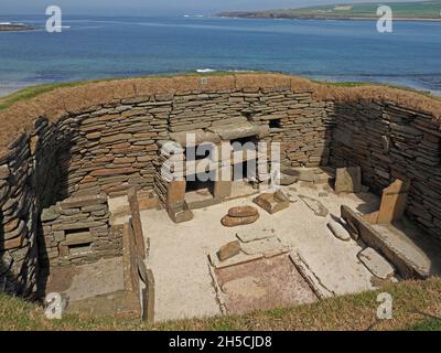 Eine restaurierte Wohnkammer mit Herd und Schlafbetten an einem sonnigen Tag im Broch of Gurness neben Eynhlow Sound, Festland, Orkney, Schottland, Großbritannien Stockfoto