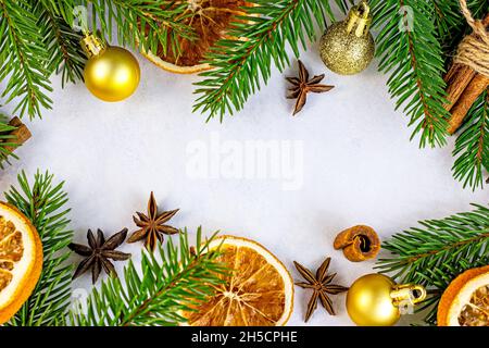 Grüne Tannenzweige, goldene Kugeln, Orangen und Gewürze als Weihnachtskranz auf weißem Hintergrund für Grußkarten. Traditioneller Winter h Stockfoto