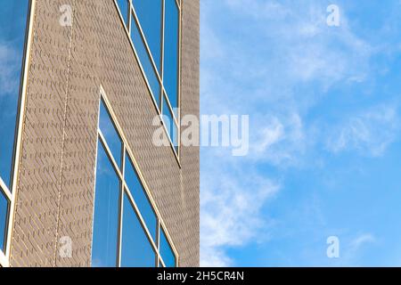 Gebäudestruktur mit braunen Ziegelsteinen und weiß gerahmten reflektierenden Glasfensterscheiben Stockfoto