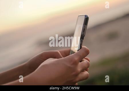 Junge Frau nutzen Smartphone für Social-Media-Chat über Sonnenuntergang Hintergrund, Zellabhängigkeit, neue Ära Technologie Stockfoto