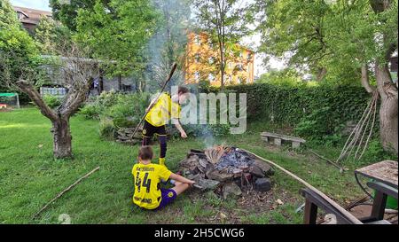 Zwei Brüder in Borussia Dortmund Trikots backen Stockbrot über einem offenen Kamin , Deutschland, Nordrhein-Westfalen, Ruhrgebiet, Dortmund Stockfoto