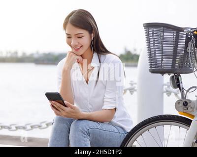 Junge Frau mit App in der Nähe der Stadt Fahrradstation.Junge Frau mit Handy für Bike-Sharing-Service. Stockfoto