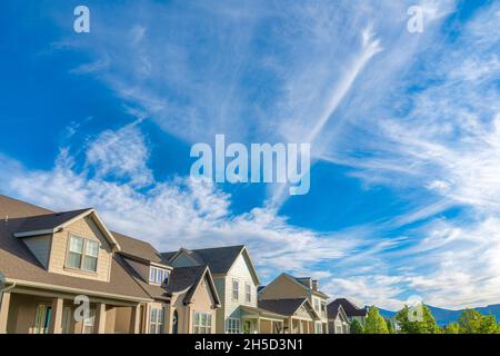Cirrus Wolken gegen den leuchtend blauen Himmel über den Wohnhäusern in Daybreak, Utah Stockfoto