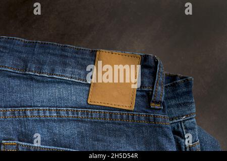 Draufsicht auf ein leeres, blank braunes Lederlabel auf blauer Denim-Jeans Stockfoto