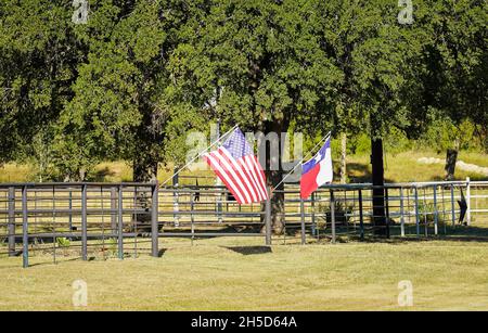 Die amerikanische und die texanische Flagge winken in der Brise auf einem Zaun Stockfoto