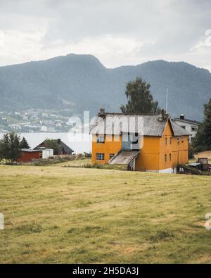 Vertikale Aufnahme eines alten Gebäudes auf einem Feld, umgeben von einem See und Bergen auf dem Land Stockfoto