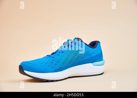 Blauer Running Sneaker aus nächster Nähe. Sport Männerschuh auf beigem Hintergrund. Fitnesskonzept Stockfoto