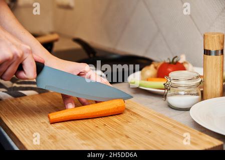 Frau kitzt Karotte auf Schneidebrett, Nahaufnahme Stockfoto