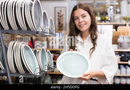 Junge Frau, die im Laden neue Gerichte auswählt Stockfoto