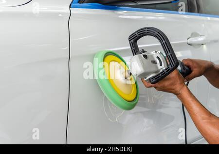 Mann bei der Arbeit Zum polieren, beschichten Autos. Polieren des Autos hilft Verunreinigungen auf der Oberfläche des Autos zu beseitigen. das Einwachsen der Auto Oberfläche c Stockfoto