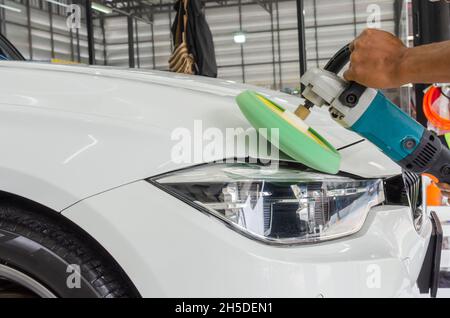 Mann bei der Arbeit Zum polieren, beschichten Autos. Polieren des Autos hilft Verunreinigungen auf der Oberfläche des Autos zu beseitigen. das Einwachsen der Auto Oberfläche c Stockfoto