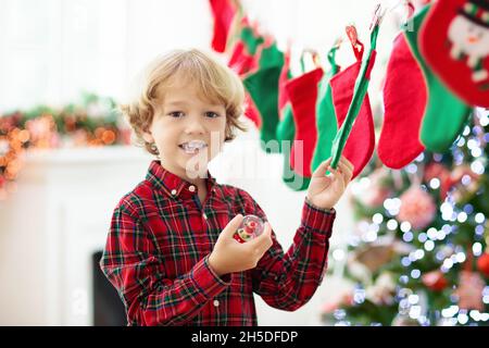 Kinder eröffnen Weihnachtsgeschenke. Kind auf der Suche nach Süßigkeiten und Geschenken im Adventskalender am Wintermorgen. Geschmückter Weihnachtsbaum Stockfoto