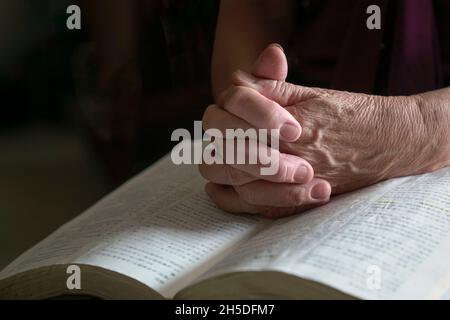 Nahaufnahme der älteren Frau Hände auf offene bibel, gefaltet im Gebet. Stockfoto