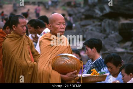 Laos: Buddhistische Mönche, die ihre täglichen Almosen am frühen Morgen im VAT Phou (Wat Phu), einem zerstörten Hindu-Tempelheiligtum Khmer (jetzt buddhistisch), in der Provinz Champasak, im Süden von Laos, durchführen. Wat Phu war ein Teil des Khmer-Reiches, das sich auf Angkor im Südwesten konzentrierte, mindestens so früh wie die Herrschaft von Yashovarman I. im frühen 10. Jahrhundert. Später wurden die ursprünglichen Gebäude ersetzt, aber einige der ursprünglichen Steinblöcke wurden wiederverwendet. Der Tempel, wie er heute steht, wurde hauptsächlich während der Koh Ker und Baphuon Perioden des 11. Jahrhunderts errichtet. Stockfoto