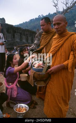 Laos: Buddhistische Mönche, die ihre täglichen Almosen am frühen Morgen im VAT Phou (Wat Phu), einem zerstörten Hindu-Tempelheiligtum Khmer (jetzt buddhistisch), in der Provinz Champasak, im Süden von Laos, durchführen. Wat Phu war ein Teil des Khmer-Reiches, das sich auf Angkor im Südwesten konzentrierte, mindestens so früh wie die Herrschaft von Yashovarman I. im frühen 10. Jahrhundert. Später wurden die ursprünglichen Gebäude ersetzt, aber einige der ursprünglichen Steinblöcke wurden wiederverwendet. Der Tempel, wie er heute steht, wurde hauptsächlich während der Koh Ker und Baphuon Perioden des 11. Jahrhunderts errichtet. Stockfoto