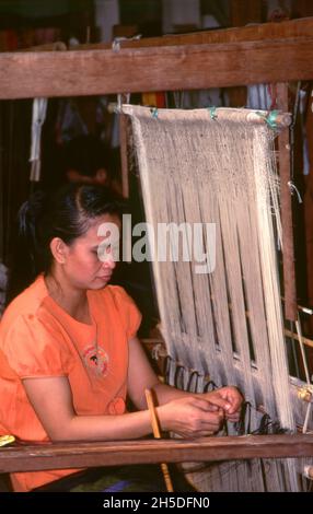 Laos: Ein Weber bei Lao Textiles, Vientiane. Lao Textiles ist ein Showroom und Webstudio mit Sitz in Vientiane, Laos. Das Unternehmen wurde 1990 von der Amerikanerin Carol Cassidy gegründet und produziert eine breite Palette von handgewebten Seidentextilien, darunter Brokat, Wandteppiche und Gardinenstoffe. Stockfoto