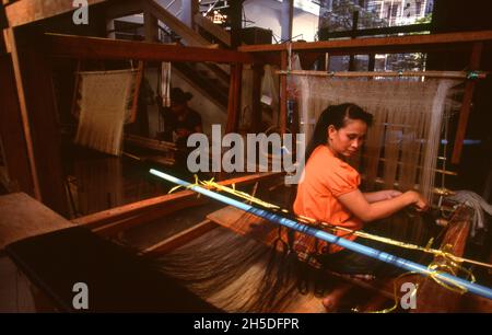 Laos: Ein Weber bei Lao Textiles, Vientiane. Lao Textiles ist ein Showroom und Webstudio mit Sitz in Vientiane, Laos. Das Unternehmen wurde 1990 von der Amerikanerin Carol Cassidy gegründet und produziert eine breite Palette von handgewebten Seidentextilien, darunter Brokat, Wandteppiche und Gardinenstoffe. Stockfoto