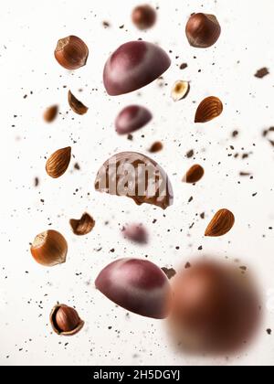 Schokoladen-Set mit Nusspraline mit Haselnüssen und Mandeln. Pralinen Levitation mit Nüssen und Kakaostücken auf weißem Hintergrund. Stockfoto