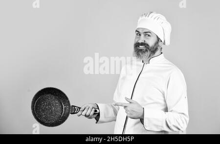 Antihaftbeschichtetes Kochgeschirr. Braten ohne Öl. Professionelle Küchenutensilien. Antihaftpfanne zum Braten. Emaillierte Kochgefäße. Mann hält Pfanne. Braten von Speisen. Gesund Stockfoto